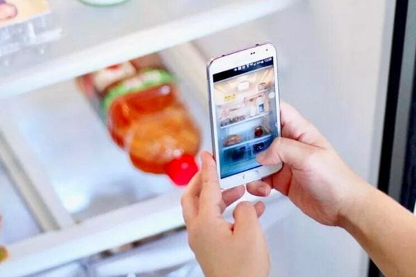 Une personne prenant en photo à l'aide de son smartphone son frigo vide