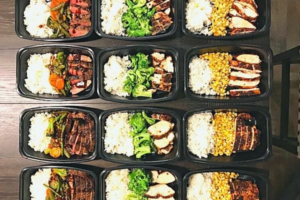 Plusieurs barquettes noires remplies d'aliments 