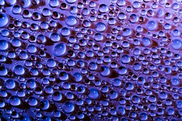 Plusieurs petites gouttes d'eau sur un fond violet 