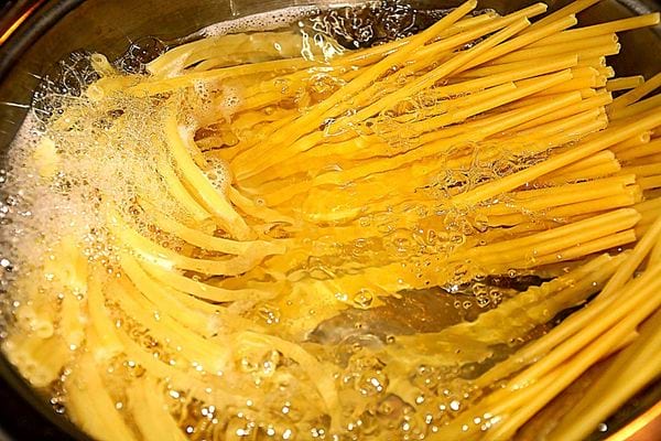 Des spaghettis en train de cuire dans une casserole d'eau
