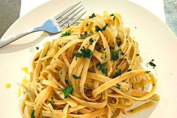 Une assiette remplie de tagliatelle avec de l'herbe aromatique et une fourchette