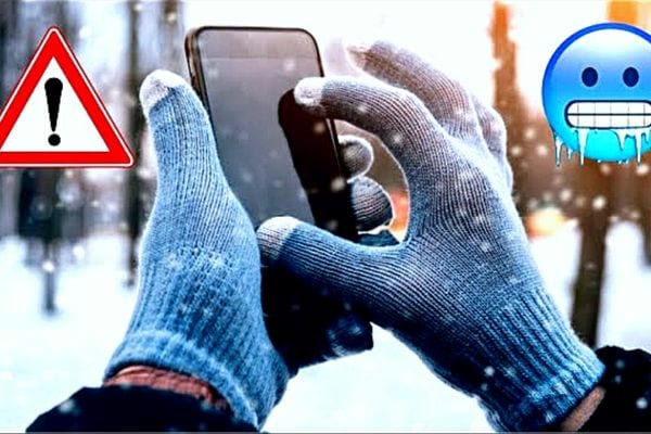 Une personne tenant un téléphone dans le froid avec des gants 