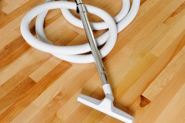 Le tube blanc d'un aspirateur sur du parquet