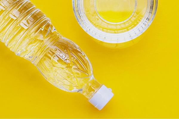 Une bouteille de vinaigre blanc sur un fond jaune