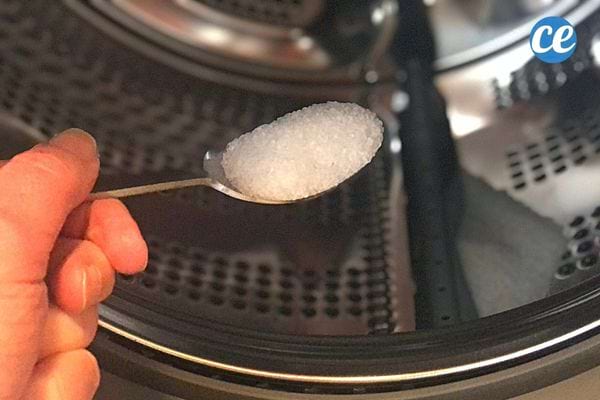 Une personne tenant une cuillère à café contenant de l'acide citrique