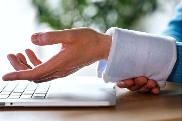 Une personne devant un ordinateur avec une compresse sur son poignet