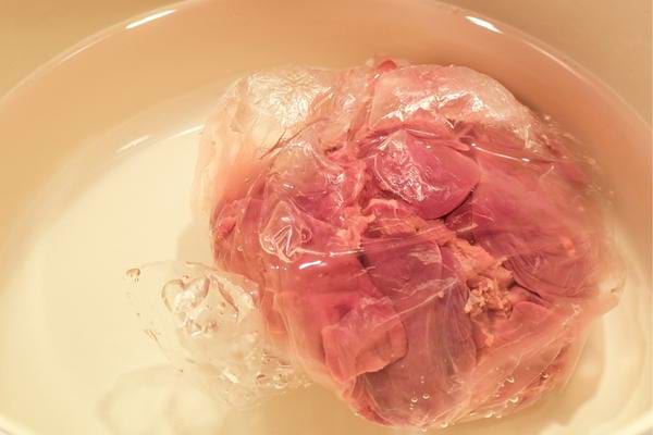 De la viande en train de décongelé sous emballage pour éviter que de l'eau coule