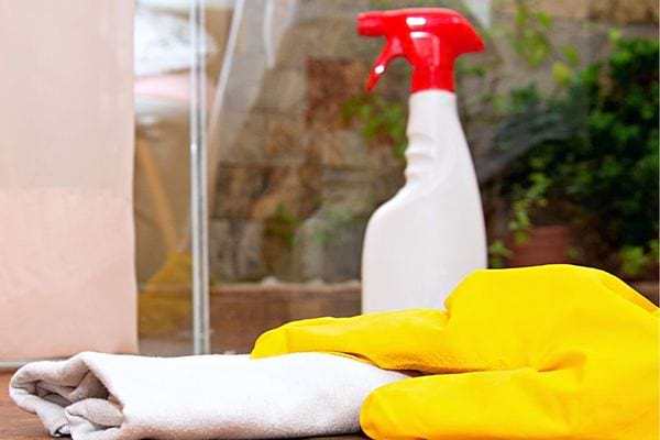 Un spray avec un bouchon rouge et une serviette blanche et des gants jaunes 