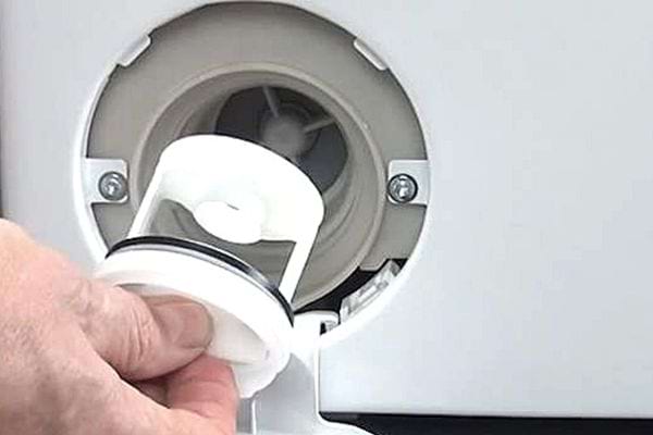 Une personne qui ouvre le filtre d'une machine à laver 
