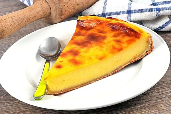 Une part de flan dans une assiette blanche et une petite cuillère à café verte