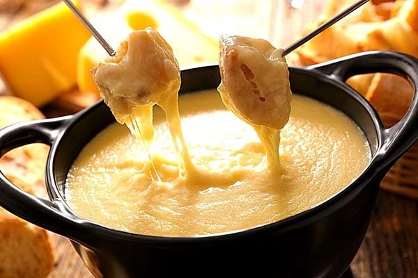 Une fondue fromagère avec deux piques contenant du pain et du fromage