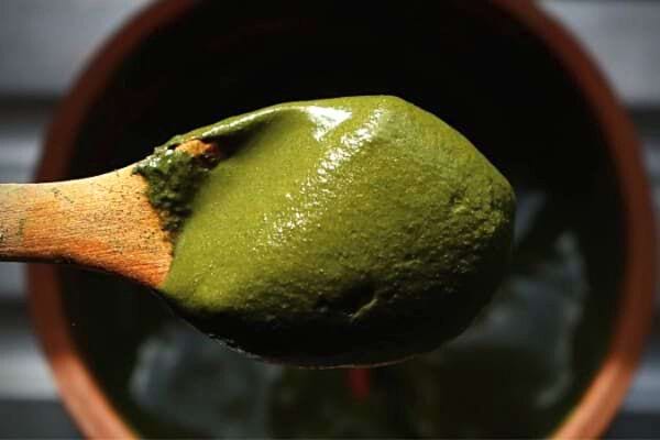 Une cuillère en bois avec du henné dessus 