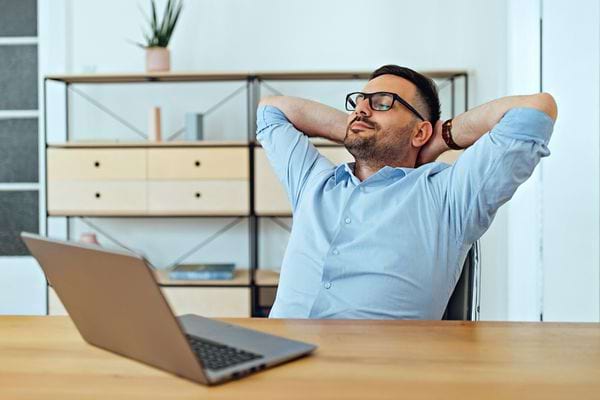 Un homme assis prenant une pause devant son ordinateur portable