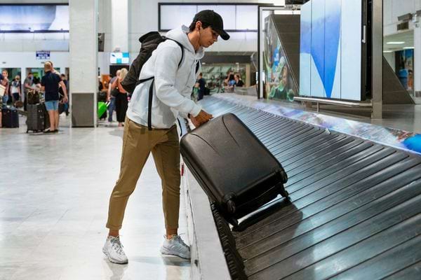 Un garçon qui prend sa valise sur le rouleau à l'aéroport 