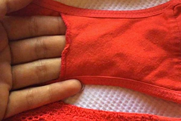 Une personne qui rentre une partie de ses doigts dans la poche d'une culotte orange