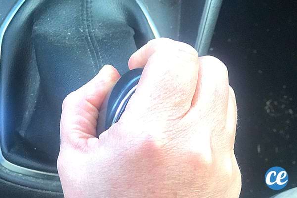 La main d'une personne sur la boîte de vitesse pour mettre sa voiture en marche arrière 