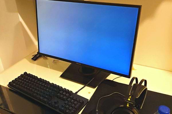 Un ordinateur fixe noir avec l'écran en veille et avec son clavier