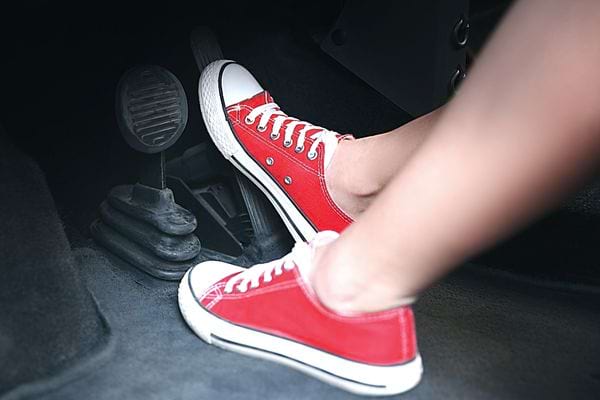 Une personne qui a des chaussures rouges dans une voiture et qui appuie sur la pédale de droite