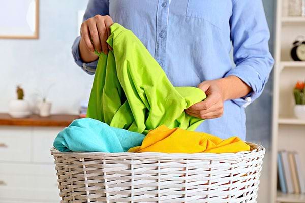 Une personne vêtu d'une longue chemise bleue en train de trier des linges