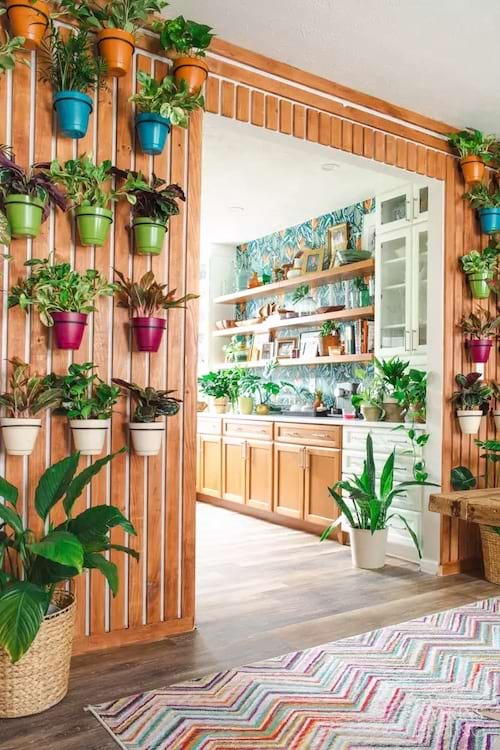 Um espaço com uma parede de ripas e plantas em seus vasos que ficam penduradas na parede