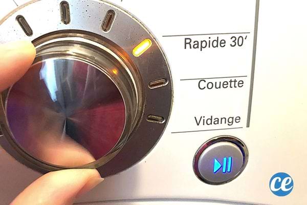 Une personne qui tourne le bouton des programmes d'une machine à laver 