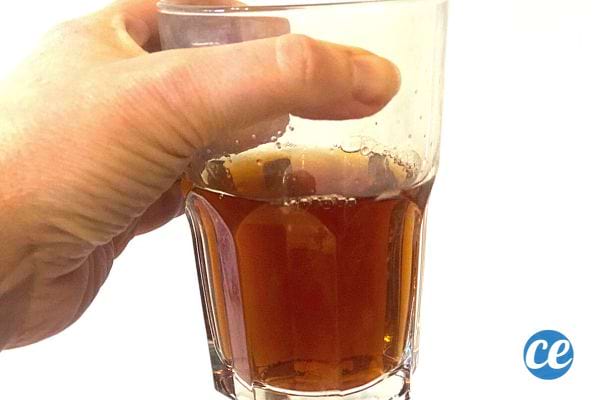 Une personne qui tient un verre contenant du thé noir