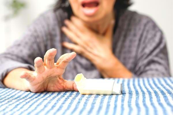 Une femme soufrant de crise d'asthme qui doit utiliser des remèdes de grand-mère pour se calmer