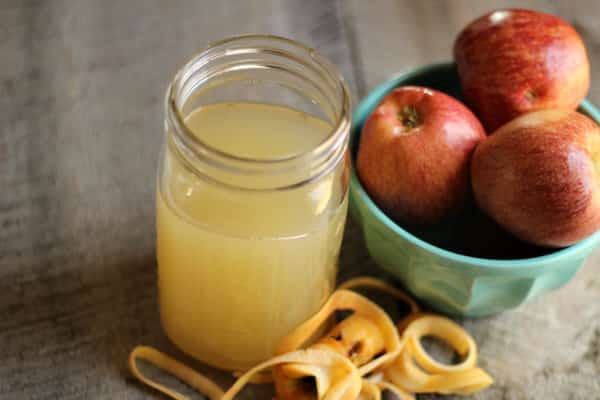 Un verre de vinaigre de cidre avec des pommes dans un bol bleu 