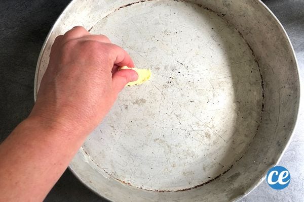 Une personne qui beurre un moule en aluminium