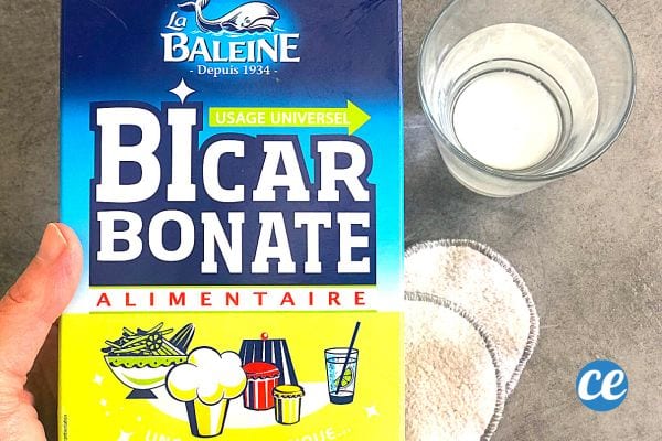 Une personne tenant un paquet de bicarbonate de soude avec un verre et deux cotons