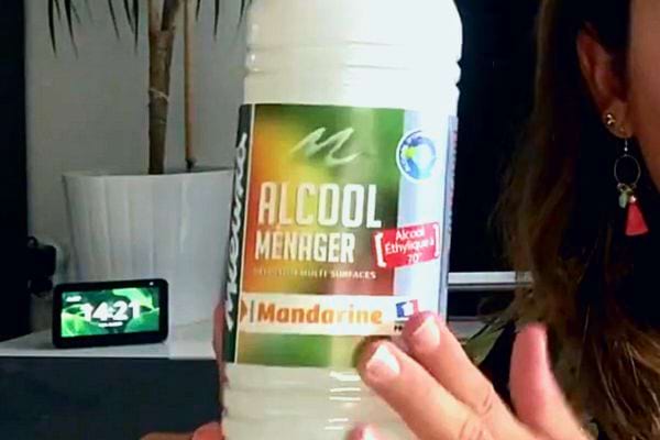 Une femme tenant une bouteille d'alcool ménager