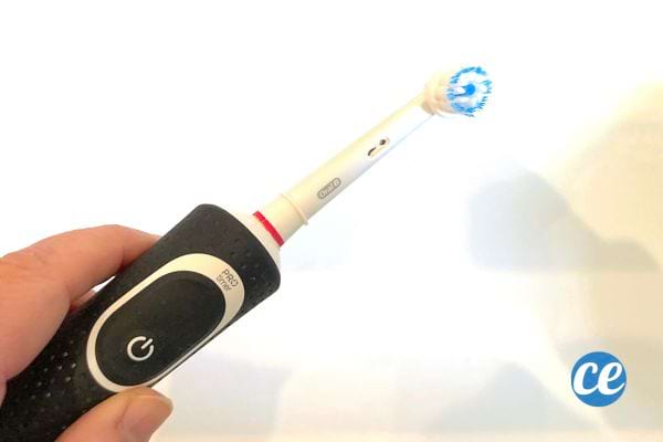 Une personne qui tient une brosse à dent électrique noire de la marque Oral-B