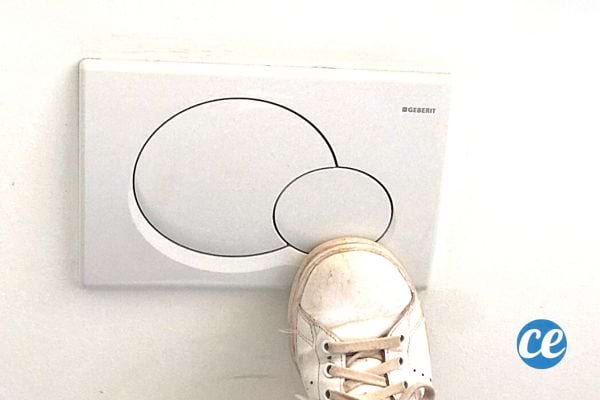 Une chaussure blanche sale sur une chasse d'eau murale 