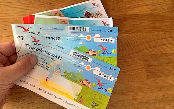 Une personne qui tient plusieurs chèques-vacances ancv 
