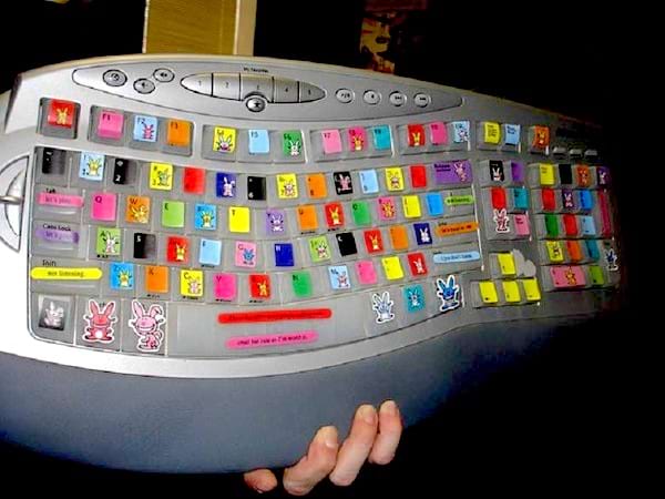 Une personne qui tient un clavier gris avec des touches multi-color