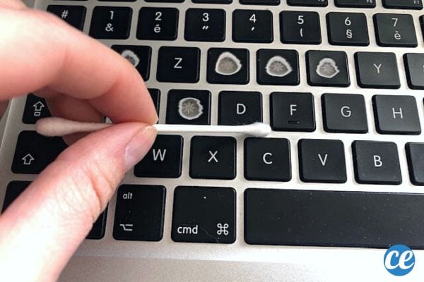 Une personne qui nettoie son clavier de MacBook avec un coton-tige 
