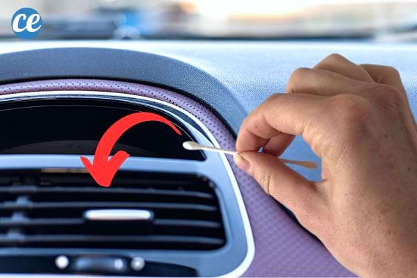 Une personne tenant un coton-tige devant un ventilateur de voiture de tableau de bord 