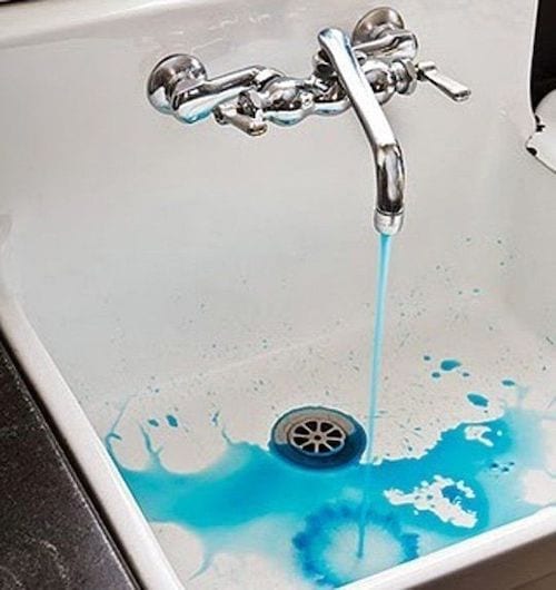 Un liquide bleu qui coule d'un robinet en argent
