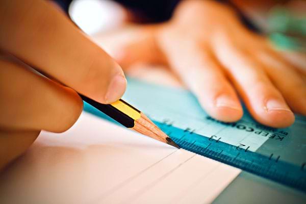 Un enfant traçant un trou avec une règle graduée et un crayon