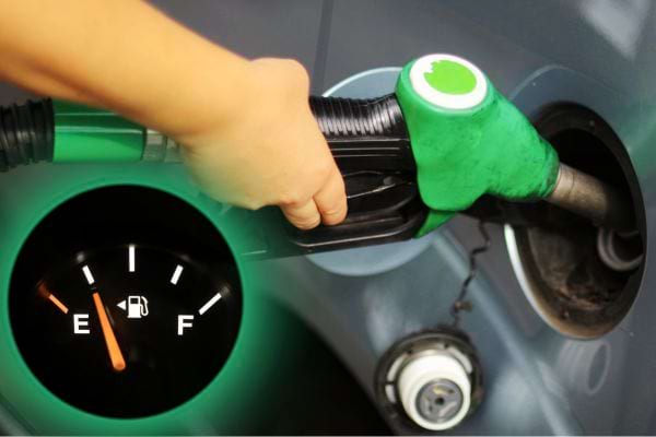 Une personne faisant de l'essence avec une pompe verte et une jauge de niveau 