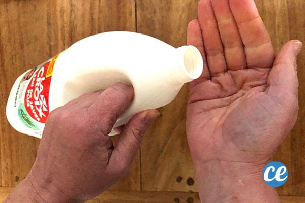 Une personne qui tient une bouteille de javel pour s'en mettre sur la main 
