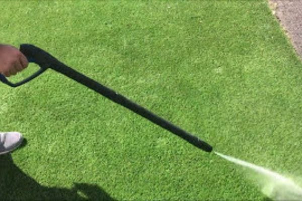 Une personne passant le Kärcher sur du gazon synthétique