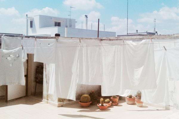 Plusieurs linges blancs qui sont étendues en extérieur sur des cordes à linges