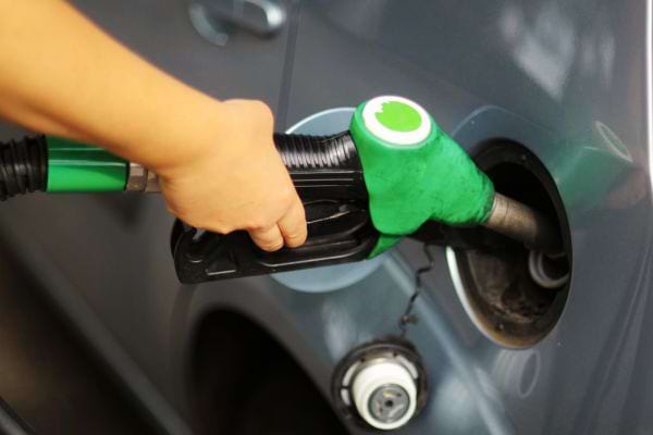 Une personne faisant de l'essence avec une pompe verte 