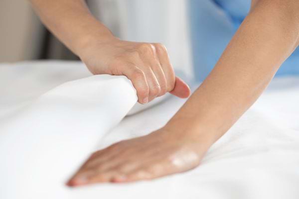 Une personne qui fait son lit avec des linges blancs