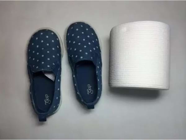 Des petites chaussures d'enfant à proximité d'un rouleau de papier toilette 