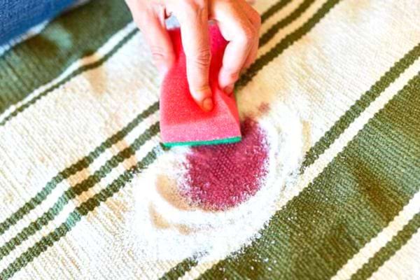 Une personne nettoyant à l'aide d'une éponge rose une tâche sur 