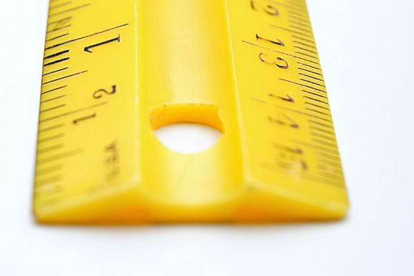 Une règle graduée jaune avec un trou