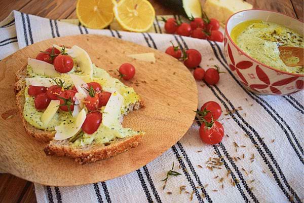Une tartine houmous, courgette, tomates et brebis avec un bol de soupe à côté