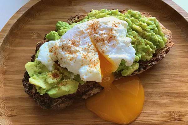 Une tartine œuf et avocat sur un plat en bois